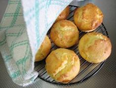 some muffins are on a wire rack with a blue and white towel next to them