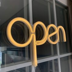 an open sign on the side of a store front window that is lit up with yellow lights