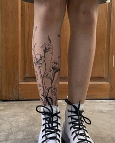 a woman's legs with flowers on them and black laces around the ankles