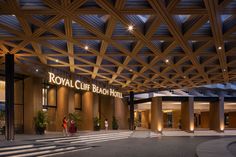 the royal club beach hotel is lit up at night, with people walking in and out