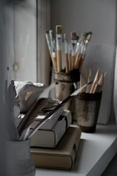 books and pencils are sitting on a shelf in front of a window sill