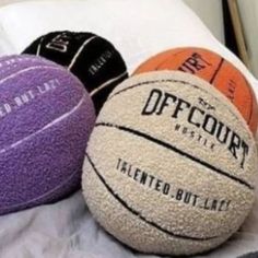 three different colored basketballs sitting on top of a bed