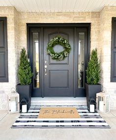 a front door with two potted plants and a welcome mat