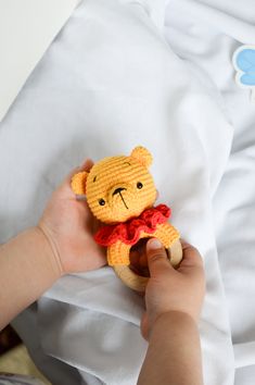 a person holding a stuffed animal on top of a white bed sheet in their hand