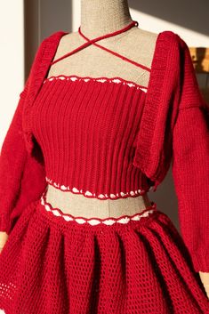 a mannequin wearing a red dress with white trims on the neckline