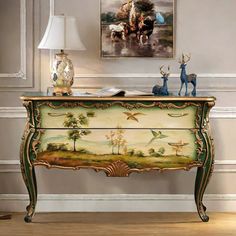 an ornate painted chest with two deer figurines on top and a painting above it