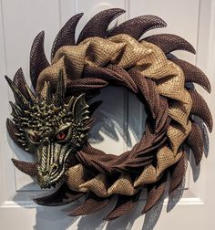 a wreath with a dragon's head is hanging on a door handle and it has brown burlap