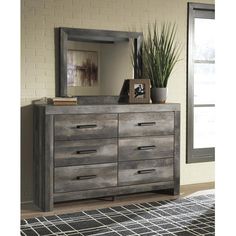 a bedroom with a dresser, mirror and potted plant