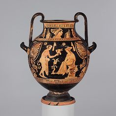 an old vase with people on it sitting on a pedestal in front of a gray background