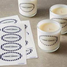 three candles sitting next to each other on top of a table with paper and envelopes