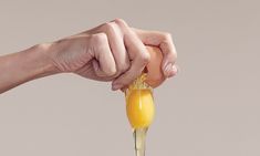 a person holding an egg over a spoon with liquid pouring from it into the bowl