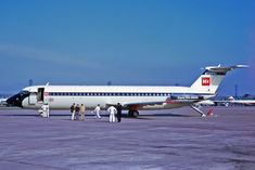 an airplane is parked on the tarmac with several people standing around it in front of it