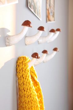 a knitted yellow scarf hanging on a white wall next to pictures and framed photos