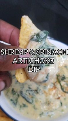 a hand holding a tortilla chip with spinach and artichoke dip