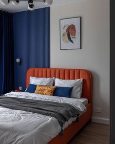 a bedroom with blue walls and white bedding, orange headboard, and an orange upholstered bed