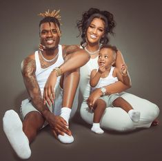 a man, woman and child sitting on the ground with their arms around each other