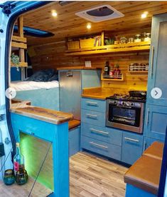 the interior of an rv with blue cabinets and wood flooring, including a stove top oven