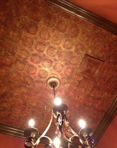 a chandelier hanging from the ceiling in a room with red walls and patterned ceilings