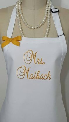 a white apron with gold lettering on it and a yellow bow tie around the neck