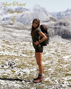 a woman standing on top of a snow covered field with a backpack in her hand