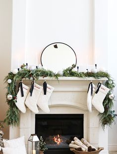 a fireplace with stockings hanging from it and candles on the mantle, along with other christmas decorations