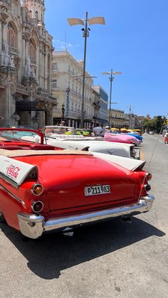 an old red car parked on the side of the road in front of a building