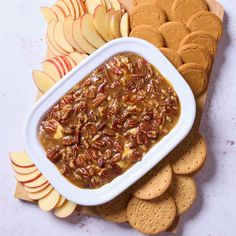 a bowl of pecan dip surrounded by crackers and apples