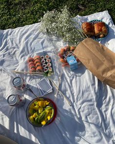 a table topped with food and drinks on top of a white cloth covered field next to grass