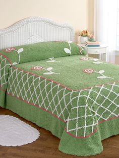 a bed with a green bedspread and white headboard