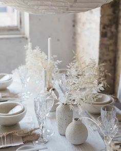 the table is set with white dishes and place settings