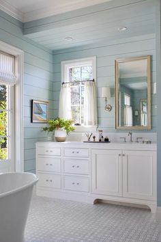 a bathroom with blue walls and white furniture in the bathtub, sink, and window