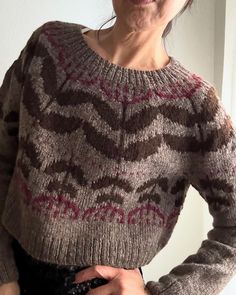 the woman is wearing a sweater with an interesting pattern on it and has her hands in her pockets