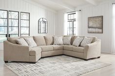 a living room with a large sectional couch and rug in front of the windows on the floor