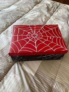 a red box sitting on top of a bed next to a cup and saucer