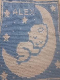 a blue and white knitted blanket with an image of a baby in the moon