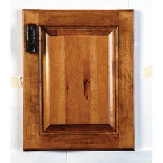 a wooden cabinet door with a black handle on the front and side panel, hanging from a white wall