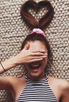 a woman covering her eyes while laying on the floor with a heart shaped object above her head