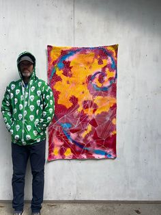 a man standing in front of a painting and wearing a green jacket with skulls on it