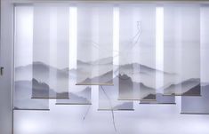 an abstract painting with mountains in the background and white vertical blinds hanging from the ceiling