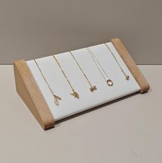 five necklaces are on display in a wooden stand with white background and light wood base