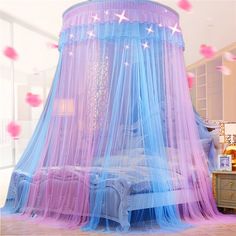 a canopy bed with pink and blue netting on it's sides, in a bedroom