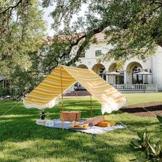 a yellow and white tent sitting on top of a lush green field next to a tree