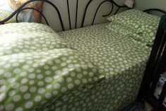 a bed with green and white polka dot sheets