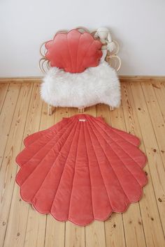 an orange shell shaped rug sitting on top of a wooden floor next to a chair