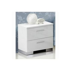 a white night stand with two drawers and a lamp on top of it, against a blue wall