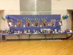 a table with pictures and balloons on it in front of a blue banner that reads, benfortht high school