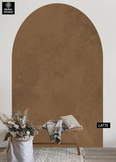 an arch in the wall is next to a vase with dried flowers and a blanket