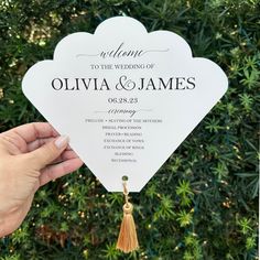 a person holding up a white fan with the words welcome to the wedding on it