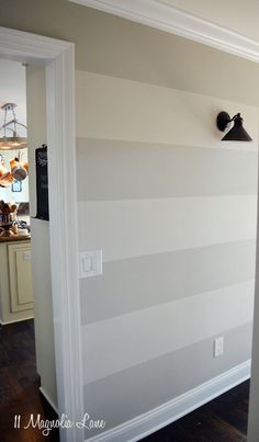 an empty room with white and gray striped wallpaper on the walls, along with a black light fixture