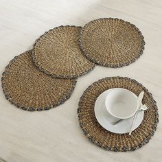 three placemats and two plates on a table with a white cup in the middle